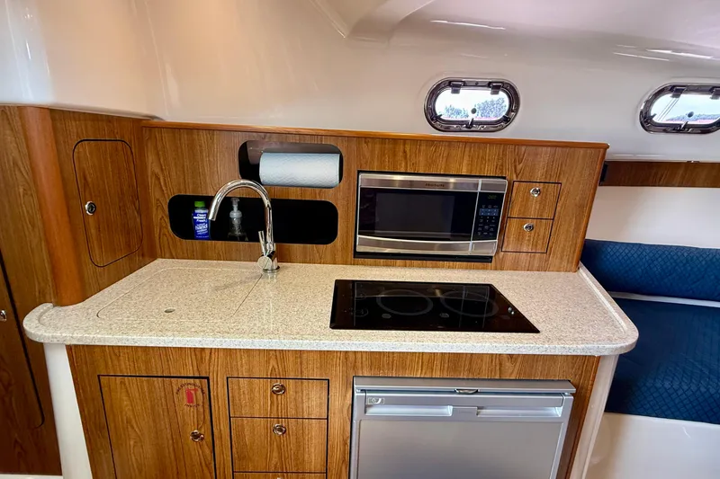 Slide: The Image of 2012 Pursuit OS 345 Offshore boat kitchen with microwave, stove, and sink. - 21