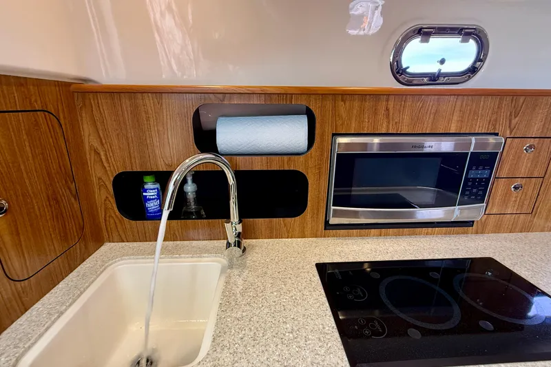 Slide: The Image of 2012 Pursuit OS 345 Offshore kitchen with sink, microwave, and stovetop. - 22