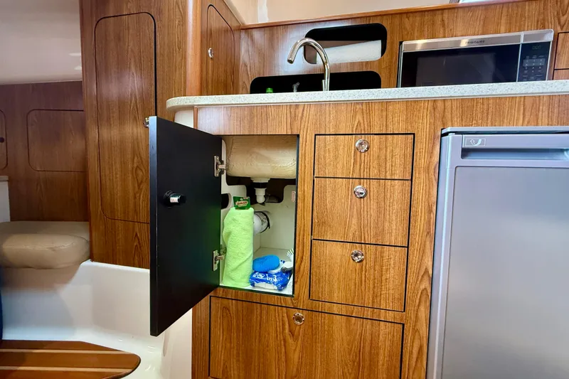 Slide: The Image of 2012 Pursuit OS 345 Offshore boat interior with wooden cabinetry and open storage. - 26