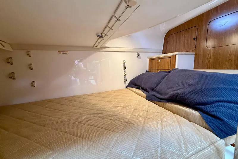Slide: The Image of Interior cabin of 2012 Pursuit OS 345 Offshore boat with cozy bedding and wooden cabinetry. - 30