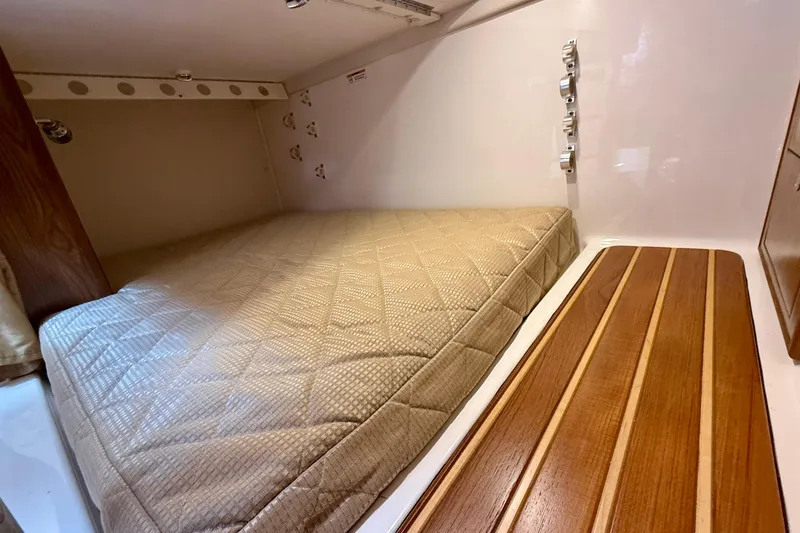 Slide: The Image of 2012 Pursuit OS 345 Offshore cabin interior with bed and wooden accents. - 31