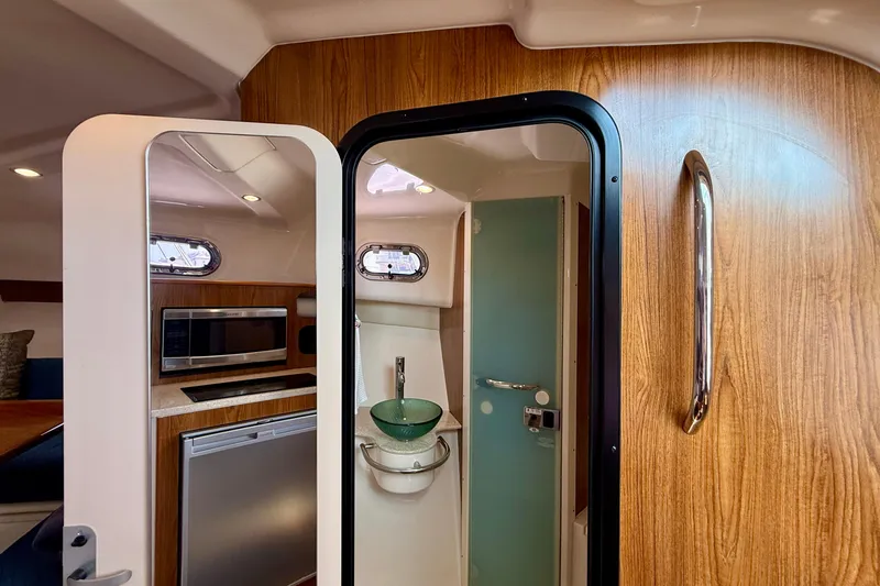 Slide: The Image of Interior of 2012 Pursuit OS 345 Offshore boat, featuring kitchenette and bathroom. - 33