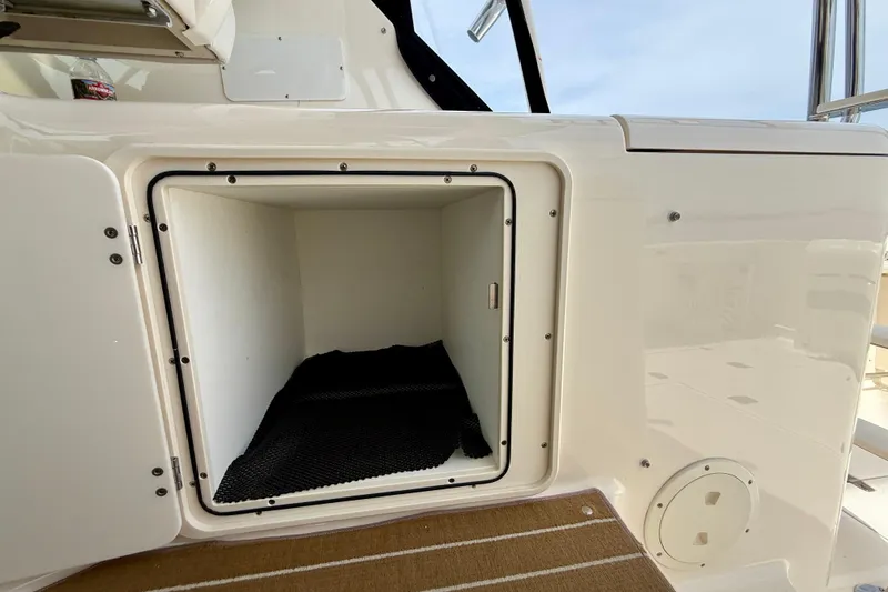 Slide: The Image of Storage compartment on a 2012 Pursuit OS 345 Offshore boat, open with black mat inside. - 57