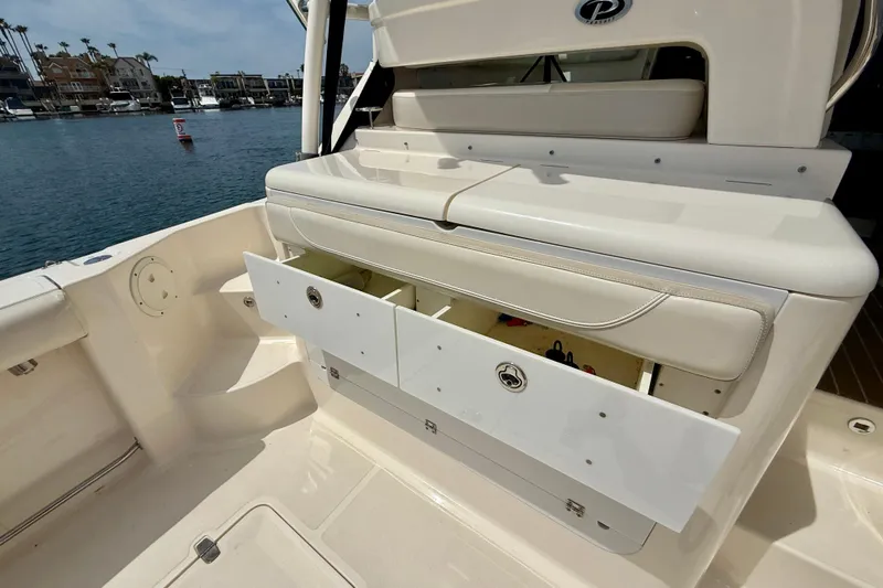 Slide: The Image of 2012 Pursuit OS 345 Offshore boat with open storage compartments, docked by waterfront homes. - 61
