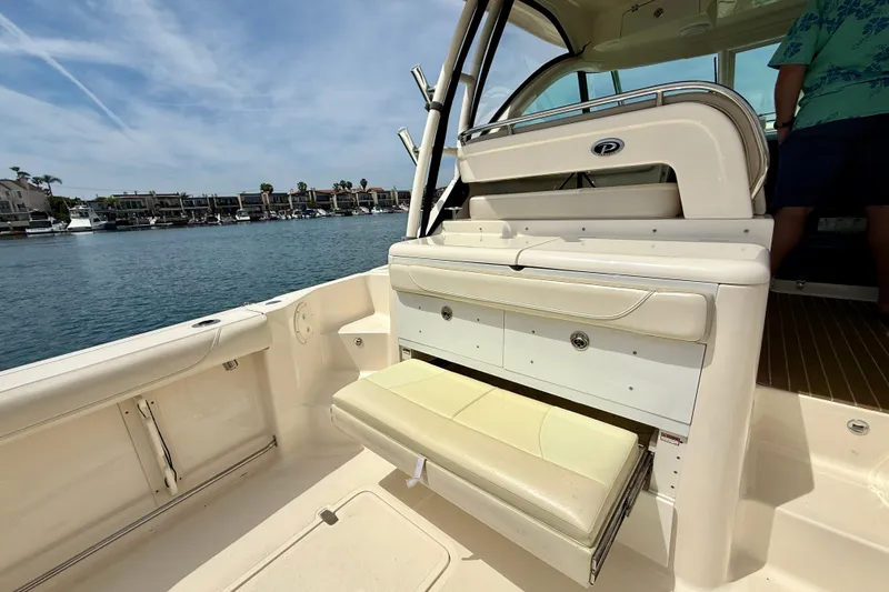 Slide: The Image of 2012 Pursuit OS 345 Offshore boat interior with seating and storage, docked near waterfront homes. - 62