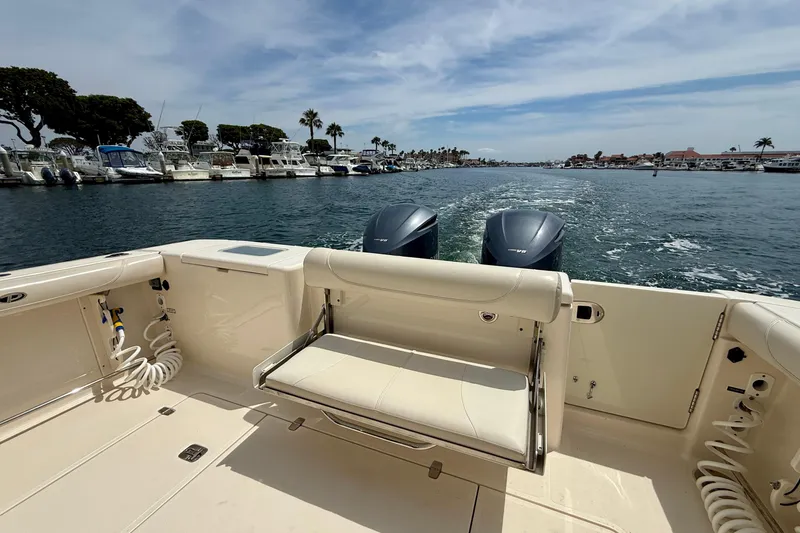 Slide: The Image of 2012 Pursuit OS 345 Offshore boat cruising on a sunny day, with twin engines visible. - 64
