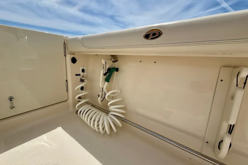 Slide: The Image of Interior view of a 2012 Pursuit OS 345 Offshore boat, featuring a coiled hose and storage area. - 65