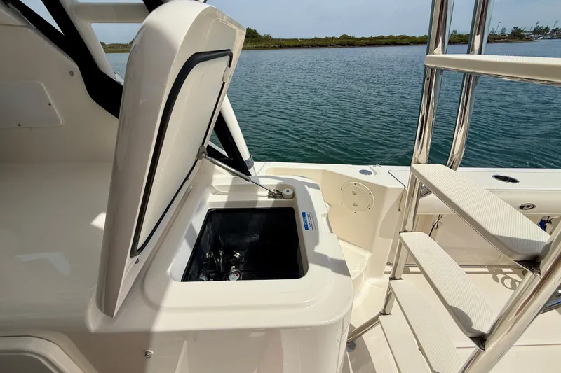 Slide: The Image of Open storage compartment on 2012 Pursuit OS 345 Offshore boat, near water. - 67