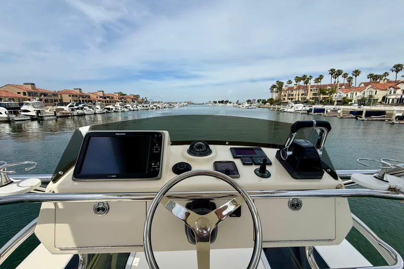 Slide: The Image of Helm view of 2012 Pursuit OS 345 Offshore boat navigating a scenic marina. - 72