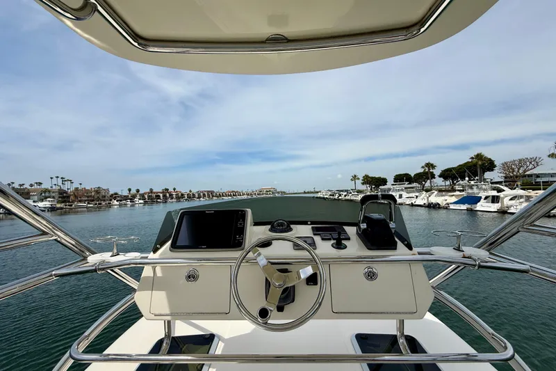 Slide: The Image of Helm view of 2012 Pursuit OS 345 Offshore boat in a marina setting. - 75
