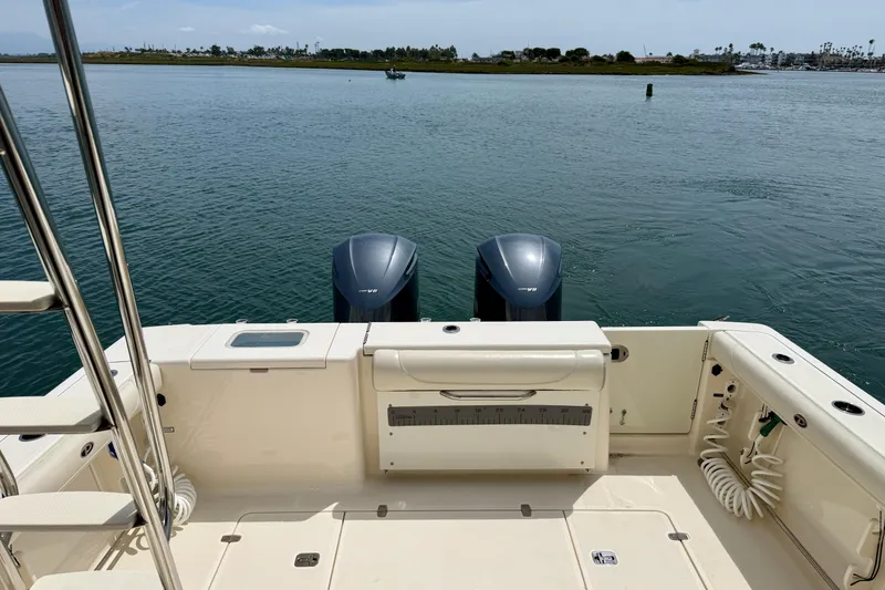 Slide: The Image of 2012 Pursuit OS 345 Offshore boat deck with dual outboard motors on calm water. - 83