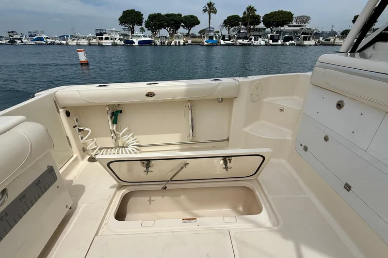 Slide: The Image of 2012 Pursuit OS 345 Offshore boat interior with open storage compartment, docked at marina. - 86