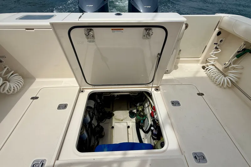 Slide: The Image of Open hatch on 2012 Pursuit OS 345 Offshore boat, revealing engine compartment. - 88