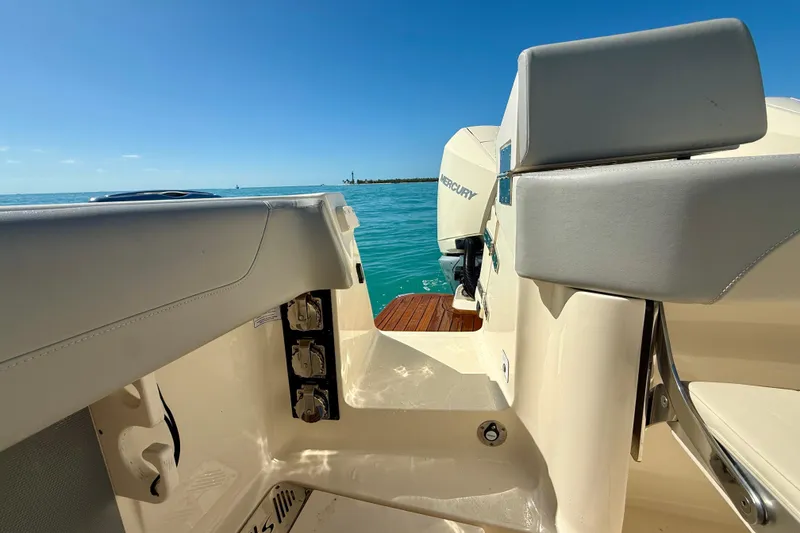 Slide: The Image of 2019 Scout 355 LXF boat interior with Mercury engine, on clear blue water. - 12