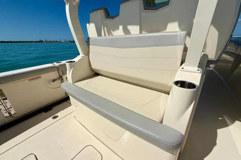 Slide: The Image of 2019 Scout 355 LXF boat seating area with cup holders, overlooking calm blue waters. - 15