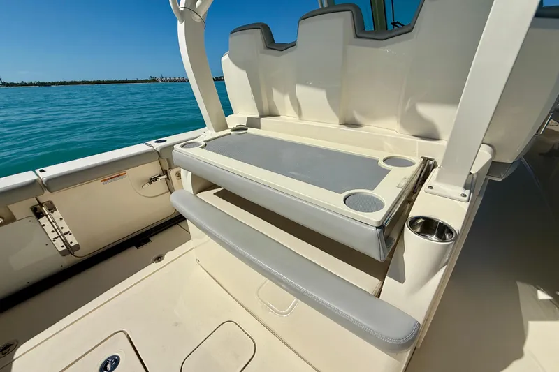 Slide: The Image of 2019 Scout 355 LXF boat interior with seating and cup holders on a sunny day. - 16