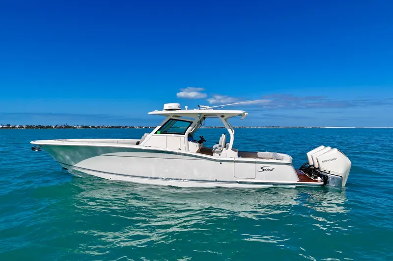 Slide: The Image of 2019 Scout 355 LXF boat on clear blue water under a bright sky. - 2