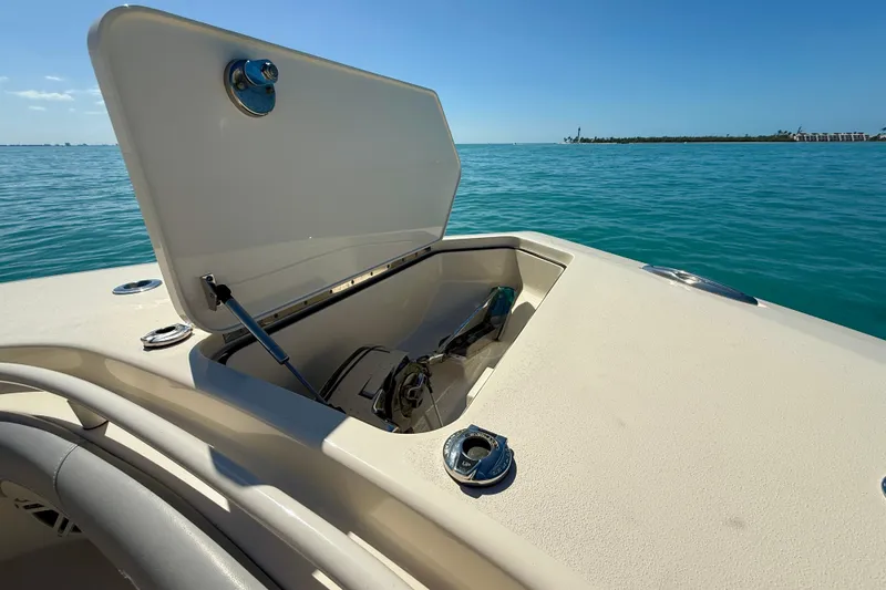 Slide: The Image of Open hatch on 2019 Scout 355 LXF boat, revealing storage compartment, with ocean backdrop. - 28