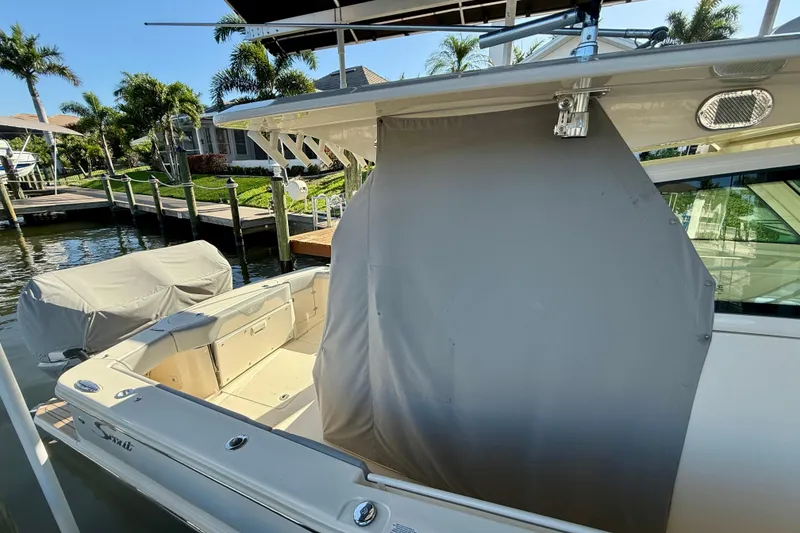 Slide: The Image of 2019 Scout 355 LXF boat docked, featuring a covered seating area and sleek design. - 36