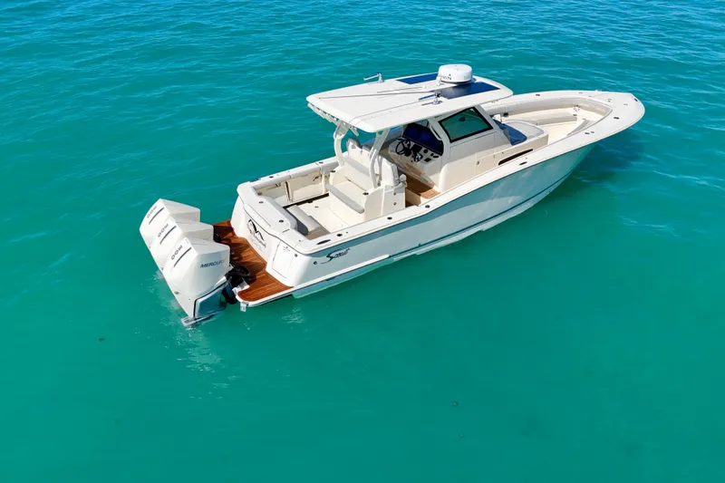 Slide: The Image of 2019 Scout 355 LXF boat on clear turquoise water, featuring dual Mercury engines. - 7