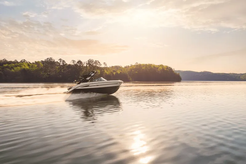 Slide: The Image of 2026 Sea Ray SDX 230 Surf cruising on a serene lake at sunset. - 23