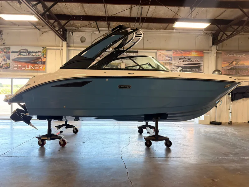 The Image of A 2026 Sea Ray SDX 230 Surf in a showroom. The boat features a blue hull. - 0
