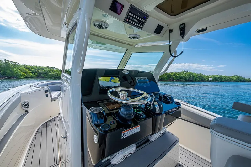 Slide: The Image of 2021 Scout 330 LXF boat helm with modern controls and scenic water view. - 24