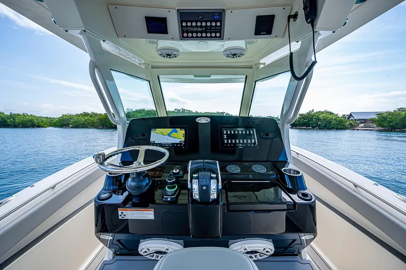 Slide: The Image of Helm of 2021 Scout 330 LXF boat with modern controls and scenic water view. - 25