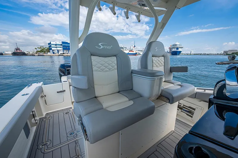 Slide: The Image of 2021 Scout 330 LXF boat interior with luxurious seating, docked in a scenic harbor. - 28