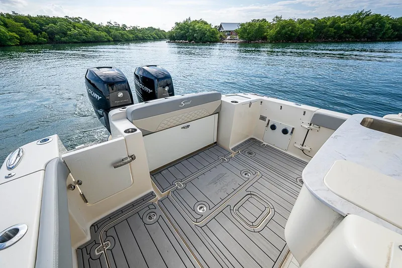 Slide: The Image of 2021 Scout 330 LXF boat deck with dual Mercury engines on calm water. - 30
