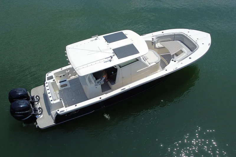 Slide: The Image of 2021 Scout 330 LXF boat with dual engines on calm water, surrounded by lush greenery. - 5
