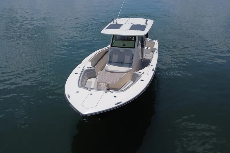 Slide: The Image of 2021 Scout 330 LXF boat cruising on calm water near lush greenery. - 6