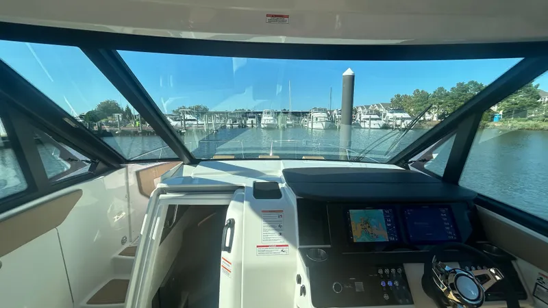Slide: The Image of The cockpit of the Sea Ray Sundancer 320 Outboard features modern instruments and a clear view of the marina. - 23