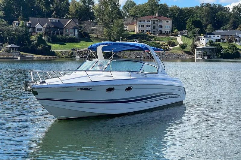 Slide: The Image of 2004 Formula 330 Sun Sport boat on a serene lake with houses in the background. - 107