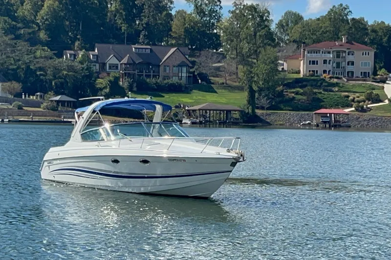 Slide: The Image of 2004 Formula 330 Sun Sport boat on a serene lake with luxury homes in the background. - 77