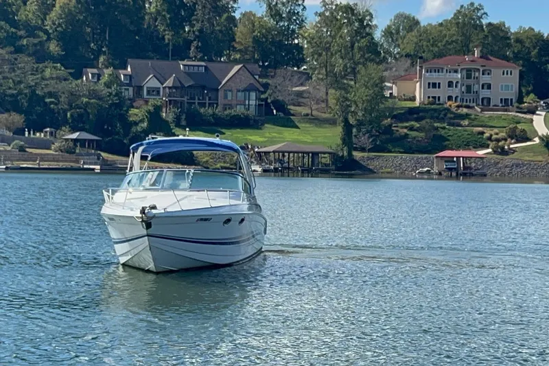Slide: The Image of 2004 Formula 330 Sun Sport boat cruising on a serene lake with luxury homes in the background. - 79