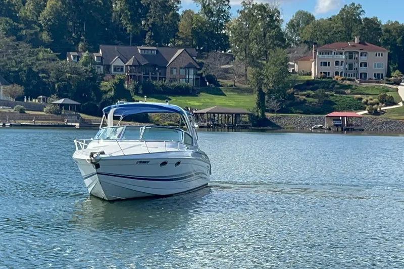 Slide: The Image of 2004 Formula 330 Sun Sport boat cruising on a scenic lake with waterfront homes. - 80