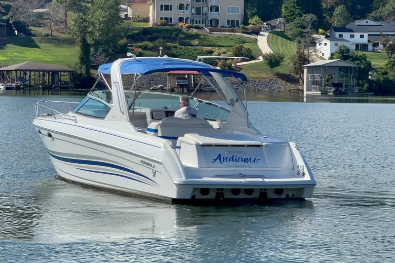 Slide: The Image of 2004 Formula 330 Sun Sport boat cruising on a serene lake near luxury homes. - 88