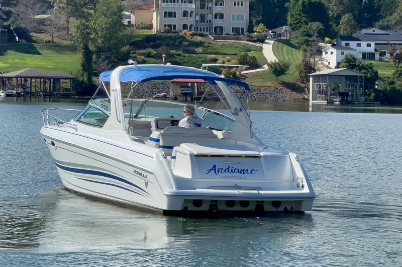 Slide: The Image of 2004 Formula 330 Sun Sport boat cruising on a serene lake near luxury homes. - 89