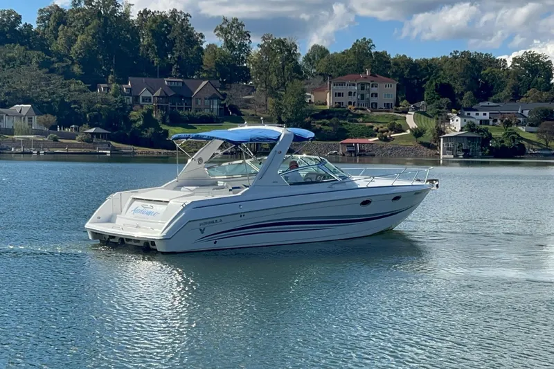 Slide: The Image of 2004 Formula 330 Sun Sport boat cruising on a serene lake with houses in the background. - 95