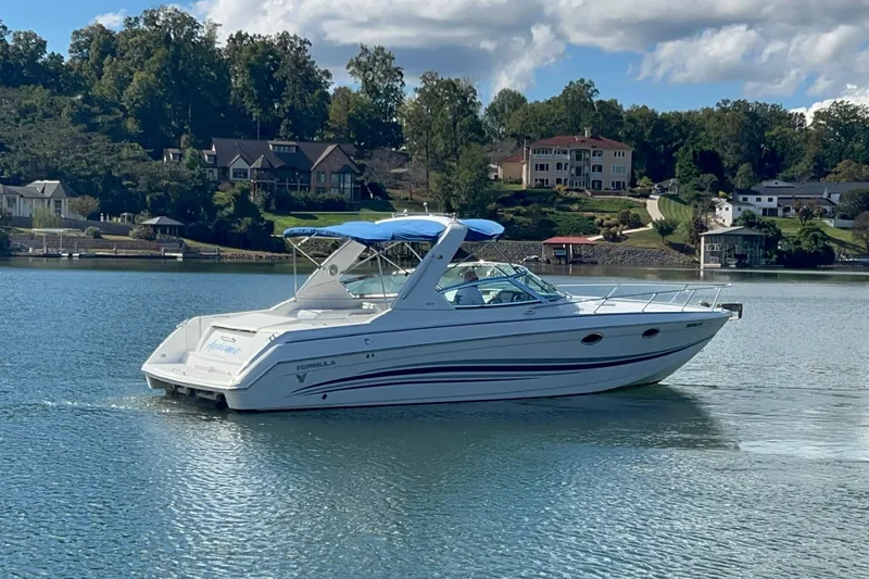 Slide: The Image of 2004 Formula 330 Sun Sport boat cruising on a serene lake with scenic background. - 96