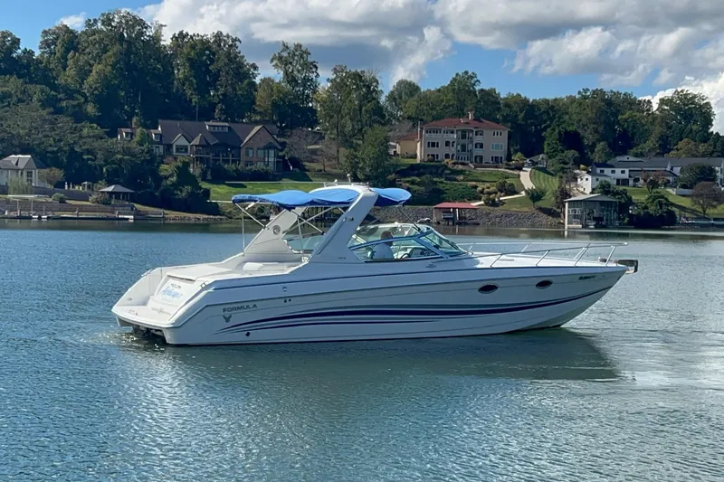 Slide: The Image of 2004 Formula 330 Sun Sport boat on a serene lake with scenic background. - 97