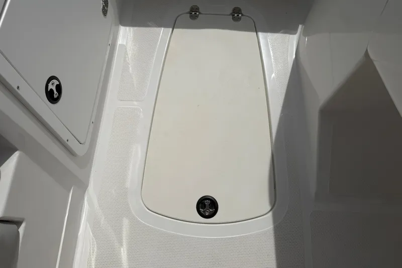 Slide: The Image of 2022 Tahoe 2150 boat storage compartment with secure latch and textured flooring. - 33