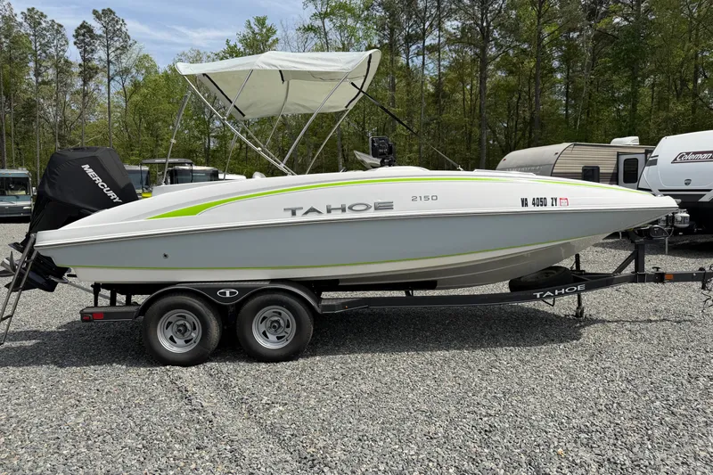 Slide: The Image of 2022 Tahoe 2150 boat on trailer, parked outdoors with trees in the background. - 36