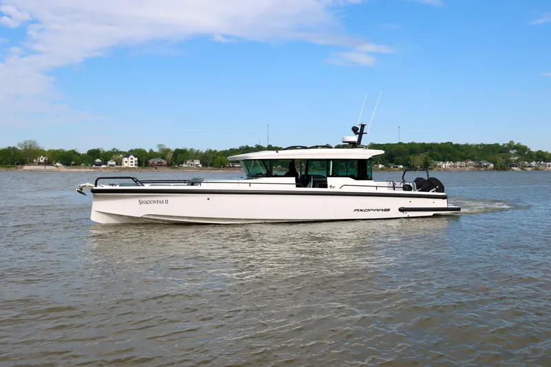 The Image of 2022 Axopar 37 XC Cross Cabin boat cruising on a calm river under a clear blue sky. - 0