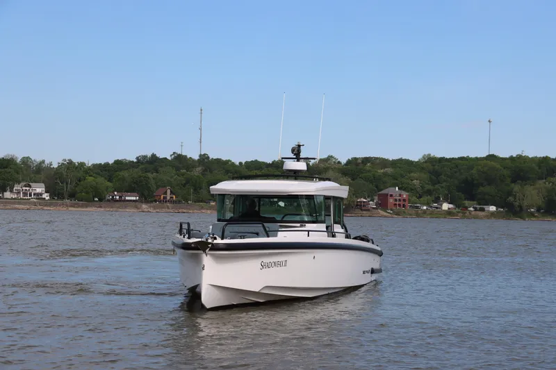 Slide: The Image of 2022 Axopar 37 XC Cross Cabin boat cruising on a calm river with scenic background. - 2