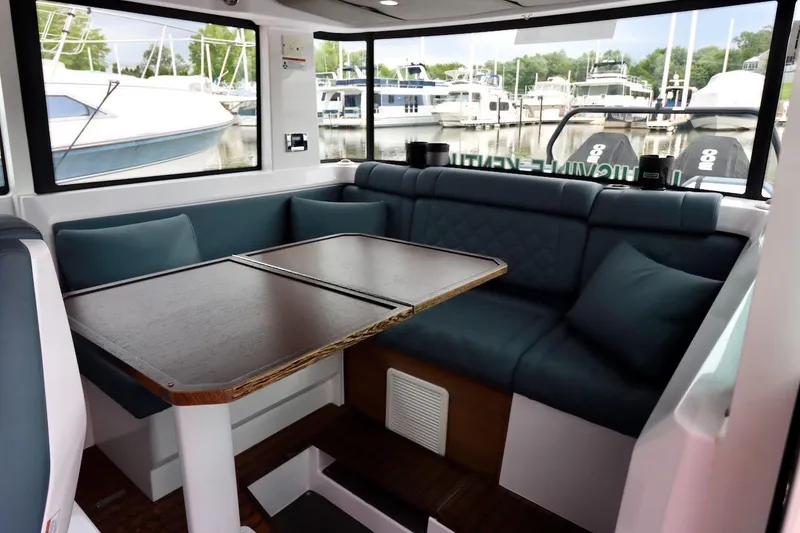 Slide: The Image of Interior of 2022 Axopar 37 XC Cross Cabin with cozy seating and table, docked at marina. - 20