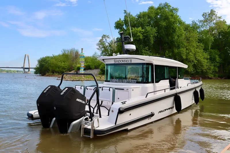 Slide: The Image of 2022 Axopar 37 XC Cross Cabin boat on a river with lush greenery and a bridge. - 4