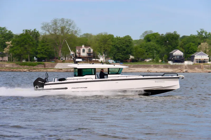 Slide: The Image of 2022 Axopar 37 XC Cross Cabin cruising on a river with lush green shoreline. - 5