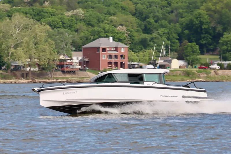 Slide: The Image of 2022 Axopar 37 XC Cross Cabin cruising on a river with lush green background. - 6